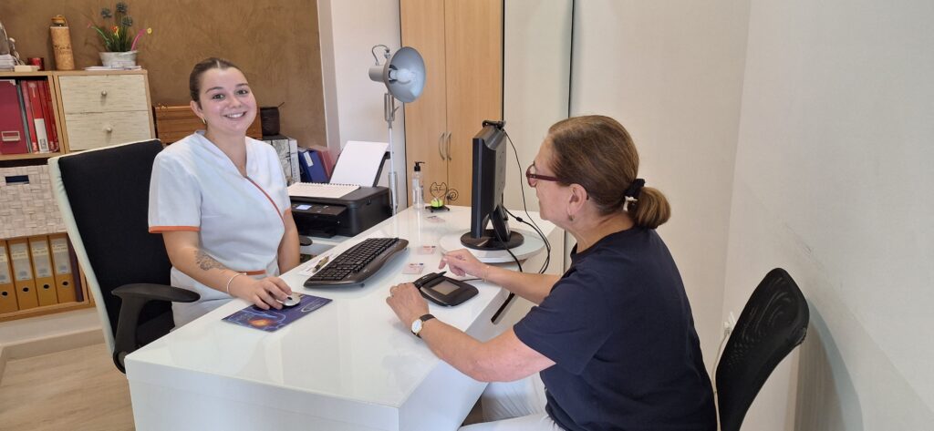 Una profesional de Policlínica CUME en Jávea atendiendo a una paciente en consulta, sentadas frente a frente en un escritorio con ordenador.
